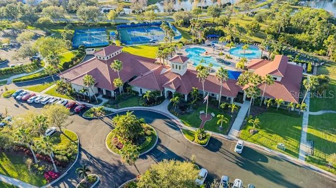 An aerial view shows a community clubhouse with a swimming pool, tennis courts, and parking — 2436 ARUGULA DRIVE, NORTH PORT, FL