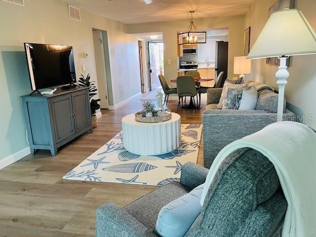 A living room with a television console, a white coffee table, and a gray sofa — 4242 HERON WAY UNIT B323, BRADENTON, FL