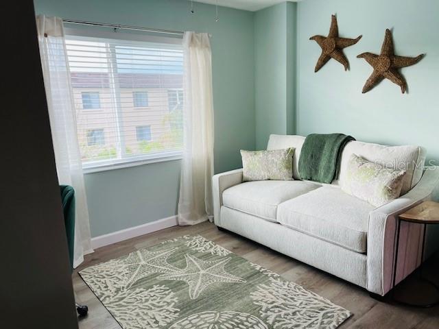 A living room features a white sofa, a starfish-patterned rug, and wall-mounted starfish decor — 4242 HERON WAY UNIT B323, BRADENTON, FL