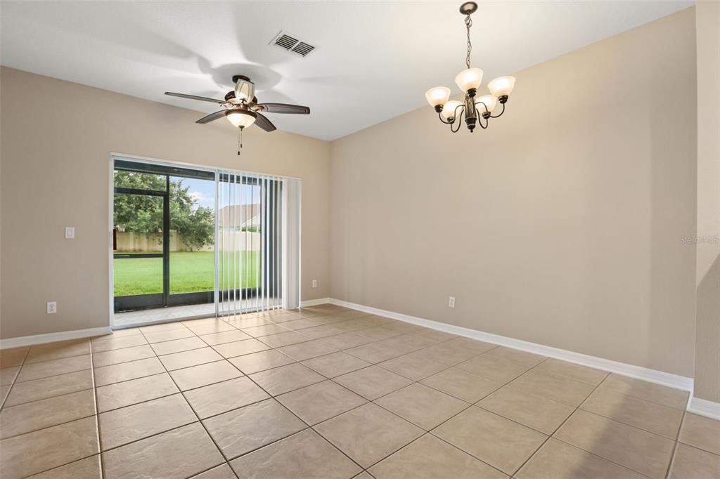 A dining room with tile flooring, a ceiling fan, a chandelier, and sliding glass doors — 10332 MANDERLEY WAY UNIT 111, ORLANDO, FL