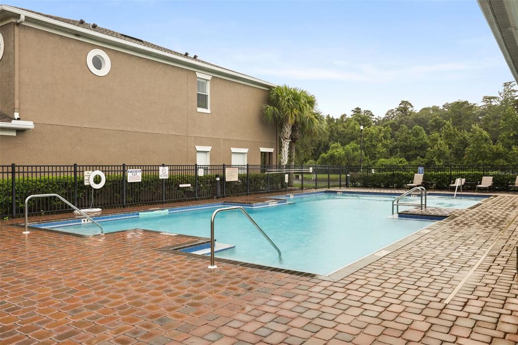 A rectangular swimming pool with a brick deck is situated next to a multi-story building — 10332 MANDERLEY WAY UNIT 111, ORLANDO, FL