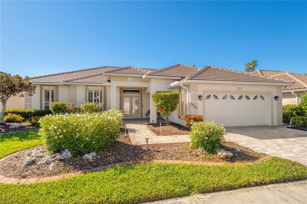 A single-story house with a tiled roof, a two-car garage, and a landscaped front yard — 5283 PINE SHADOW LANE, NORTH PORT, FL