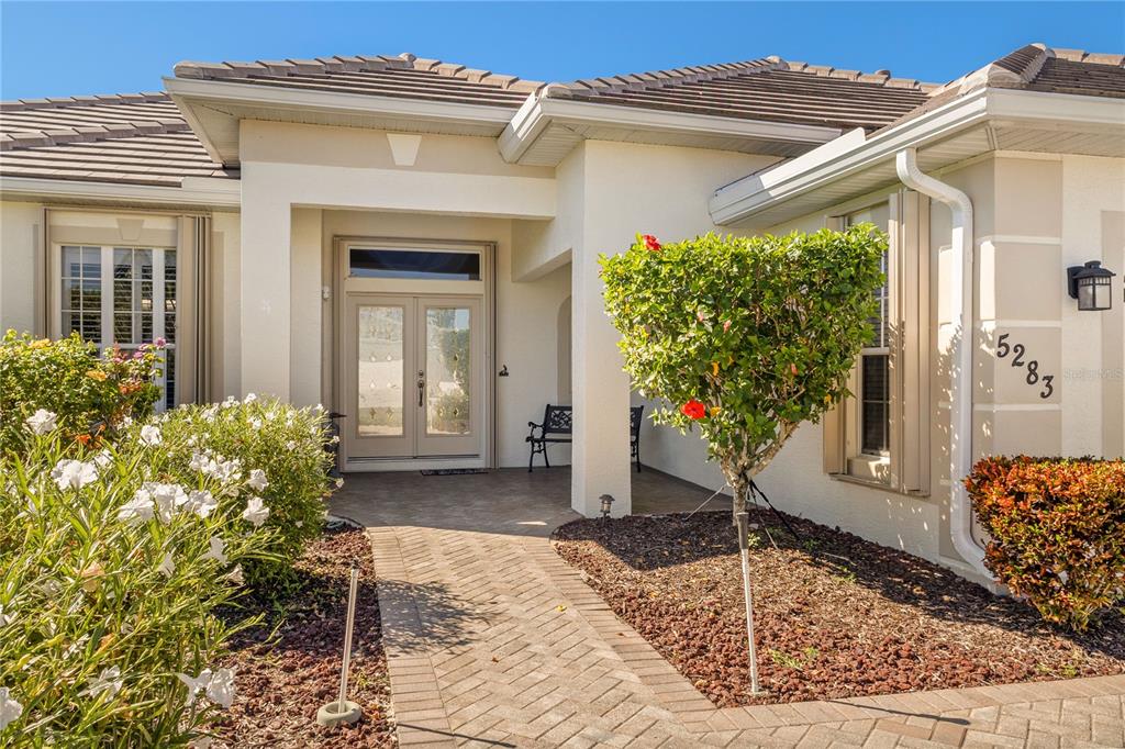 A paved walkway leads to the front entrance of a house with a tiled roof — 5283 PINE SHADOW LANE, NORTH PORT, FL