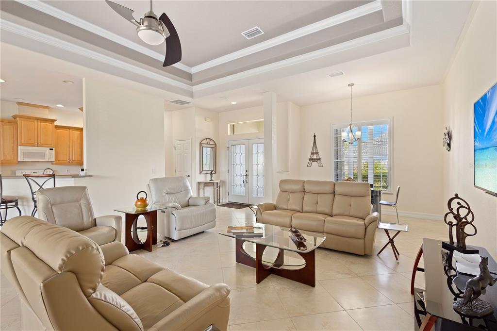 A living room with light tile floors, beige leather furniture, and a tray ceiling — 5283 PINE SHADOW LANE, NORTH PORT, FL