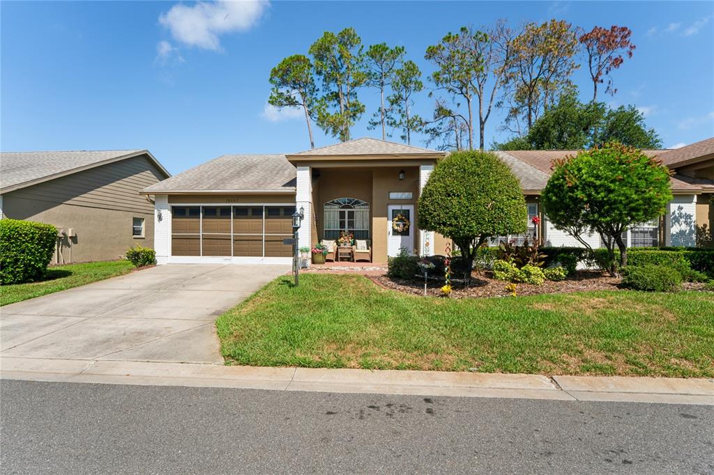 A single-story suburban house with a two-car garage, front porch, and landscaped yard — 18607 BENT PINE DRIVE, HUDSON, FL