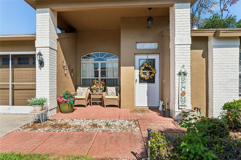 The front exterior of a house features a brick porch, white pillars, and a door — 18607 BENT PINE DRIVE, HUDSON, FL