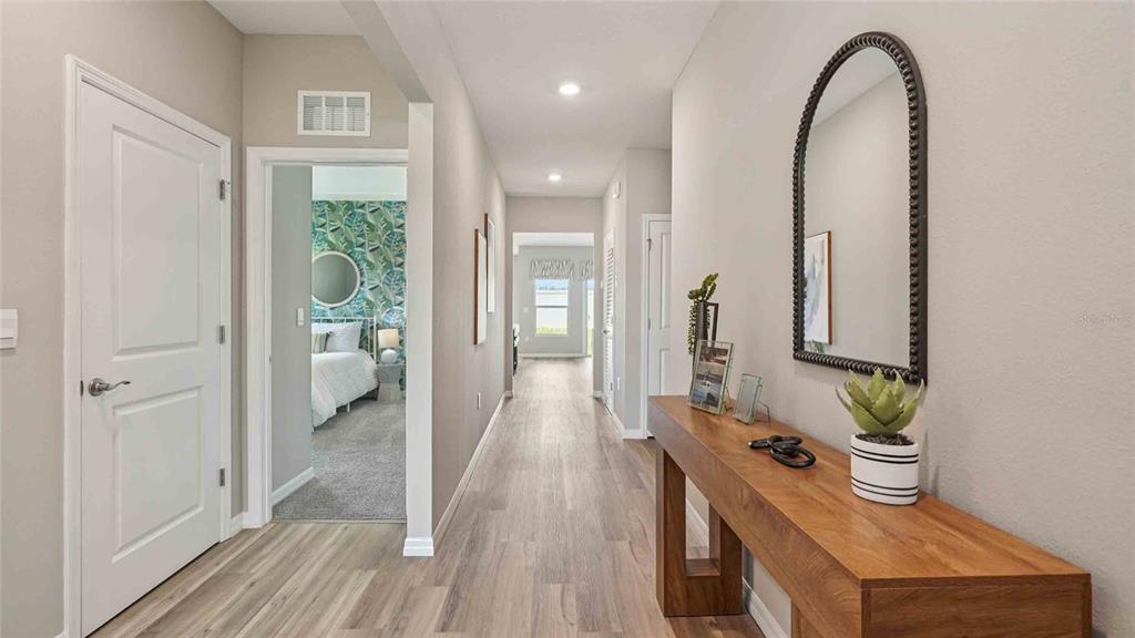 A hallway with wood-look flooring, a wooden console table, and a mirror leads to a bedroom — 24246 NW 13TH BOULEVARD, NEWBERRY, FL