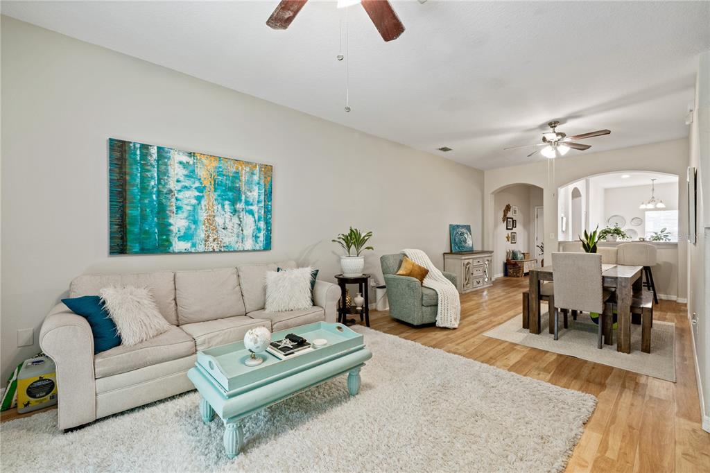 A living room with a beige sofa, light blue coffee table, and adjacent dining area — 2349 WILLIMETTE DRIVE, WESLEY CHAPEL, FL