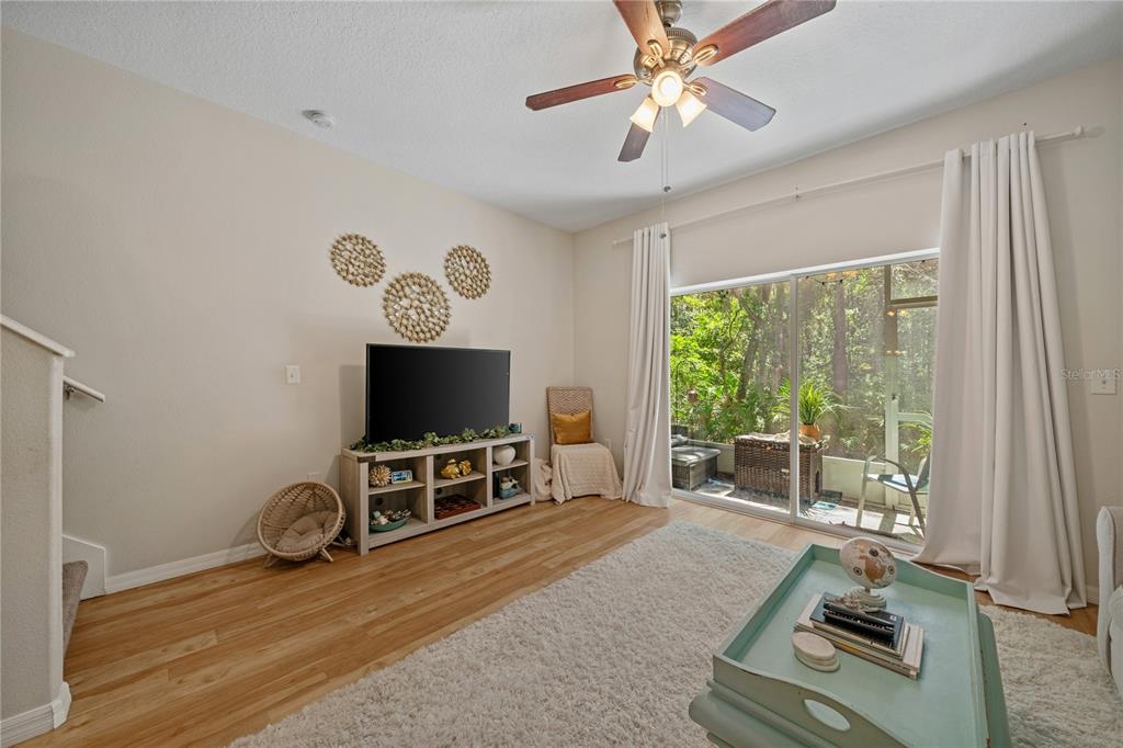 A living room features a television on a console, a ceiling fan, and sliding doors — 2349 WILLIMETTE DRIVE, WESLEY CHAPEL, FL