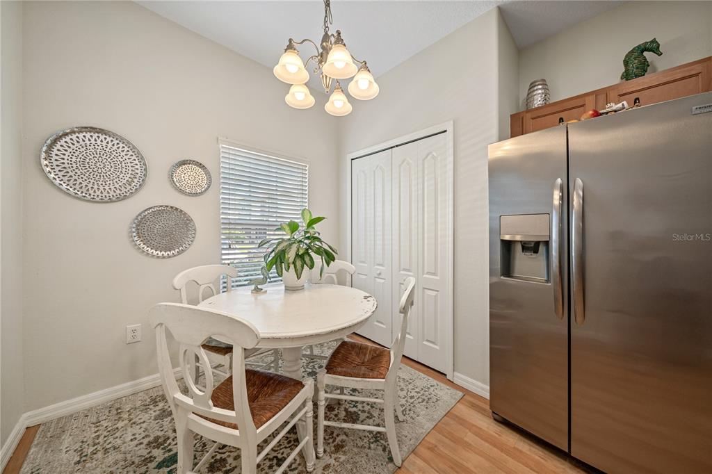 A dining area features a round white table, four chairs, and a stainless steel refrigerator — 2349 WILLIMETTE DRIVE, WESLEY CHAPEL, FL