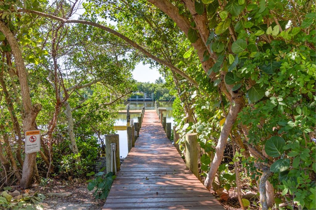 A wooden dock extends through lush green trees toward a calm body of water — 191 KETTLE HARBOR DRIVE, PLACIDA, FL