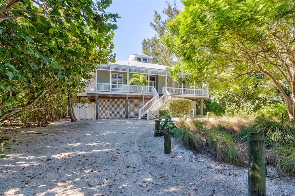 A stilt house with a wraparound porch sits above a shell-covered driveway surrounded by trees — 191 KETTLE HARBOR DRIVE, PLACIDA, FL