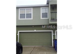 A two-story house exterior features a green stucco facade, a double garage, and an upper balcony — 3911 PEMBERLY PINES CIRCLE, ST CLOUD, FL
