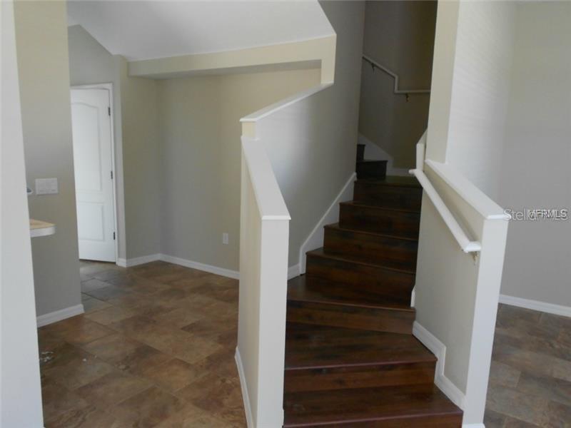 A staircase with dark wood treads leads upward from a room with tiled flooring — 3911 PEMBERLY PINES CIRCLE, ST CLOUD, FL