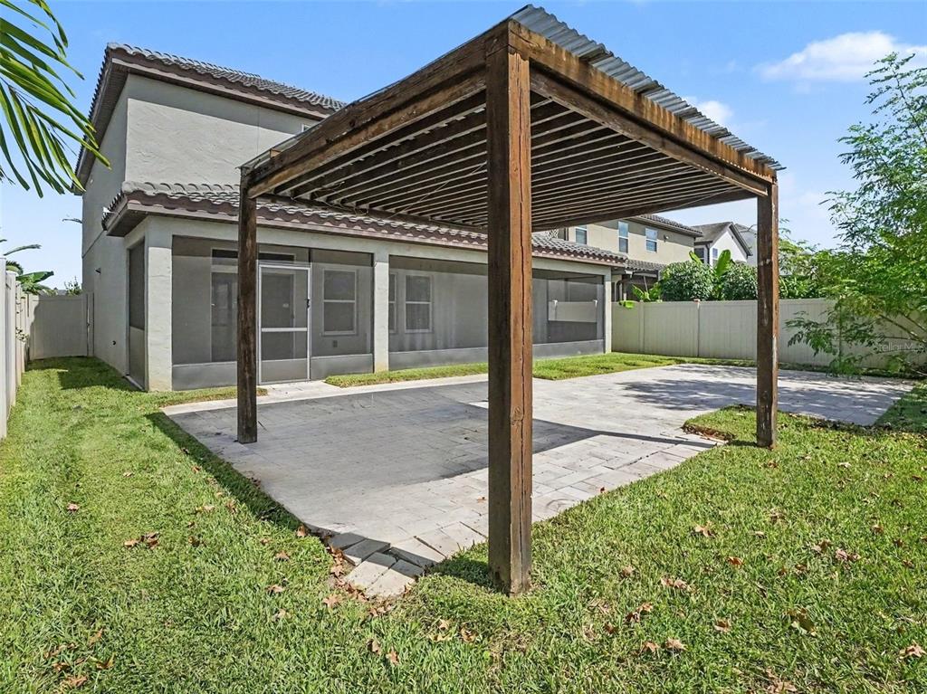 A backyard patio features a wooden pergola with a corrugated metal roof and screen enclosure — 3208 STONEWYCK STREET, ORLANDO, FL