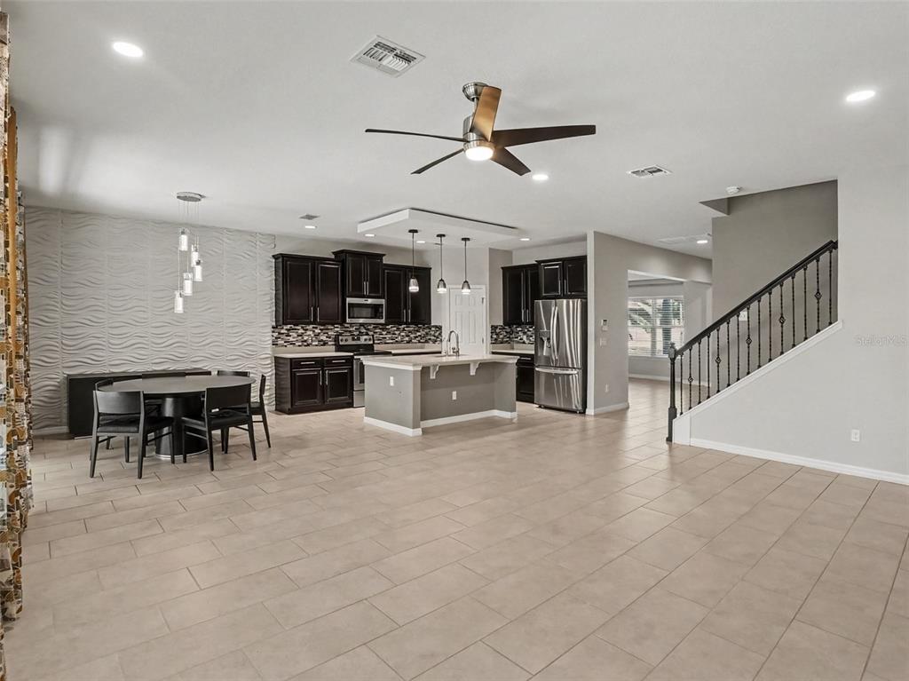An open-concept kitchen and dining area features dark cabinetry, a central island, and tile flooring — 3208 STONEWYCK STREET, ORLANDO, FL