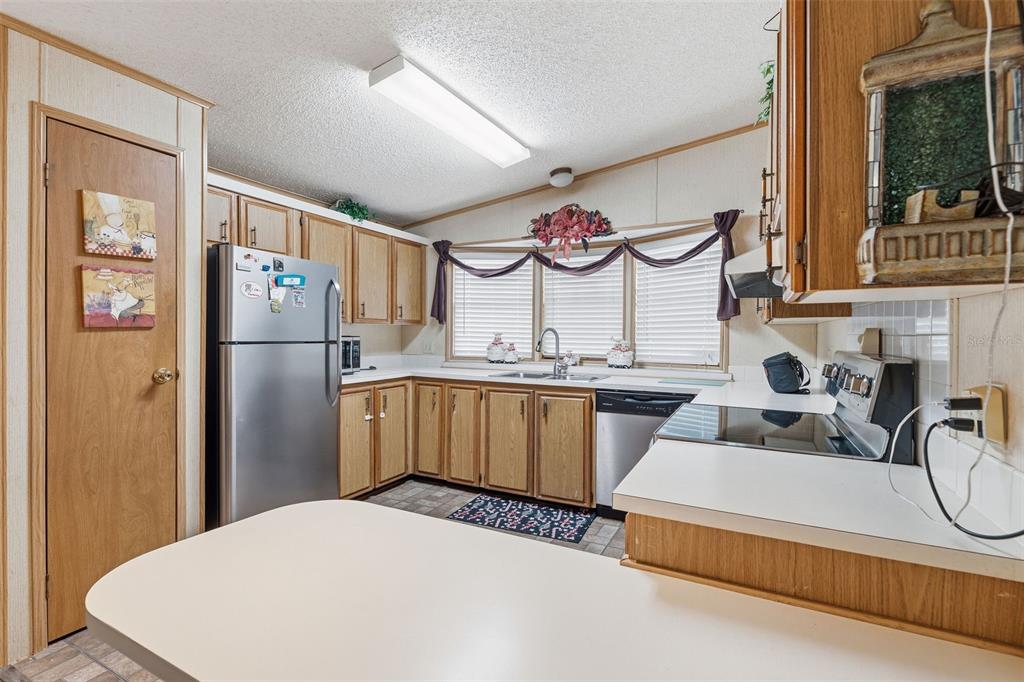 A kitchen features wood cabinets, stainless steel appliances, white countertops, and a window over the sink — 410 DOLPHIN DRIVE S, OLDSMAR, FL