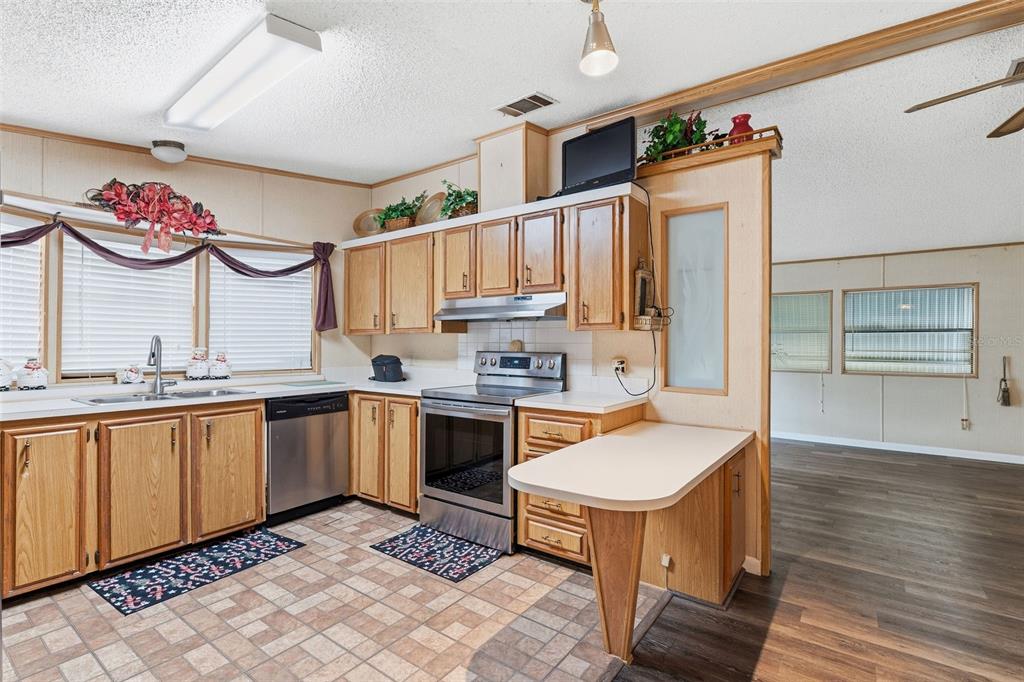 A kitchen with wood cabinets, stainless steel appliances, and a small peninsula counter — 410 DOLPHIN DRIVE S, OLDSMAR, FL