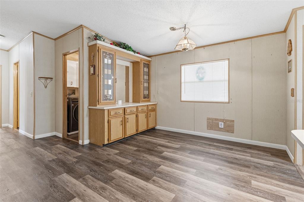 A dining area features wood-look vinyl flooring, light-colored panel walls, and a built-in oak hutch — 410 DOLPHIN DRIVE S, OLDSMAR, FL