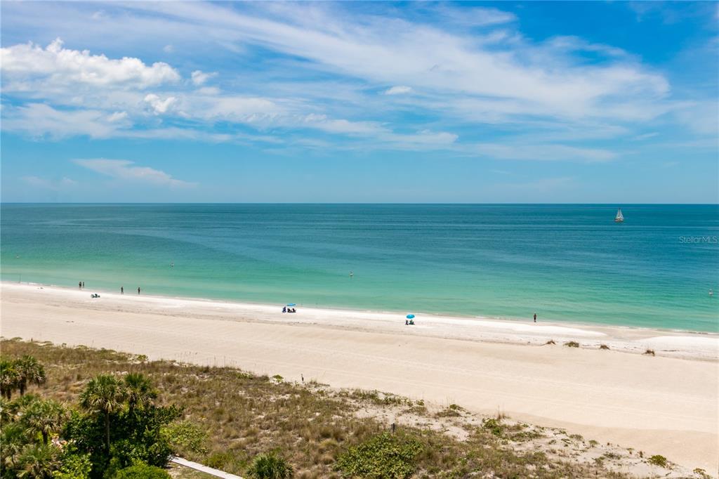 An elevated view of a sandy beach with turquoise water and a distant sailboat — 1380 GULF BOULEVARD UNIT 805, CLEARWATER, FL