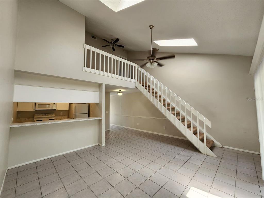 A living room with tile flooring, a staircase, and an open kitchen with a breakfast bar — 2760 GRAY FOX LANE, ORLANDO, FL