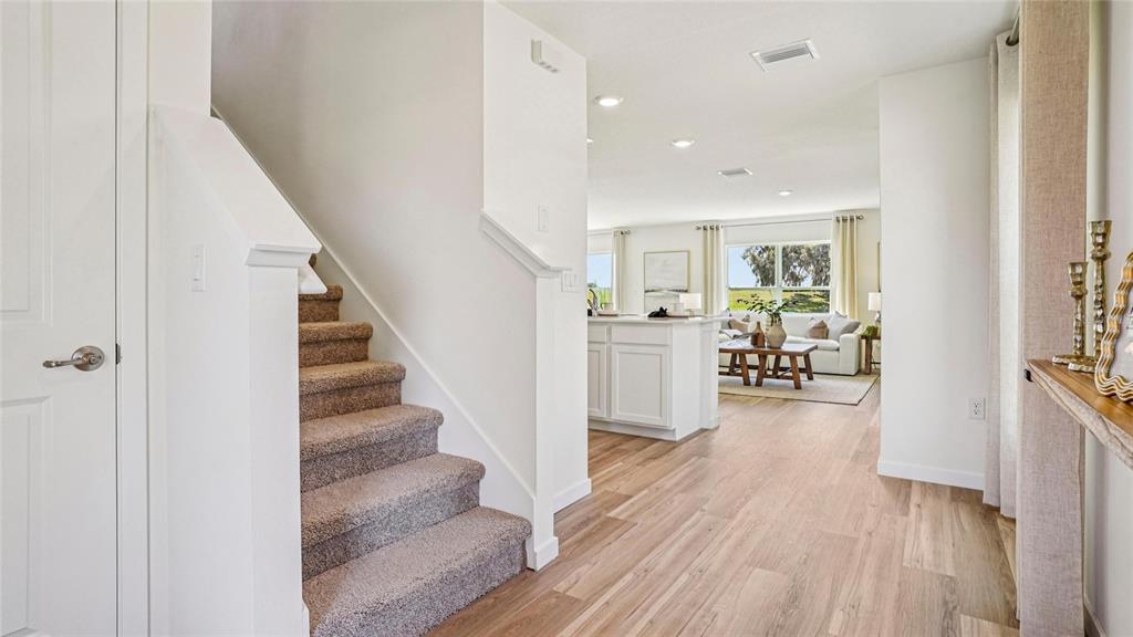 A carpeted staircase leads to an open-concept living area with light wood flooring — 2118 NE 33RD LANE, OCALA, FL