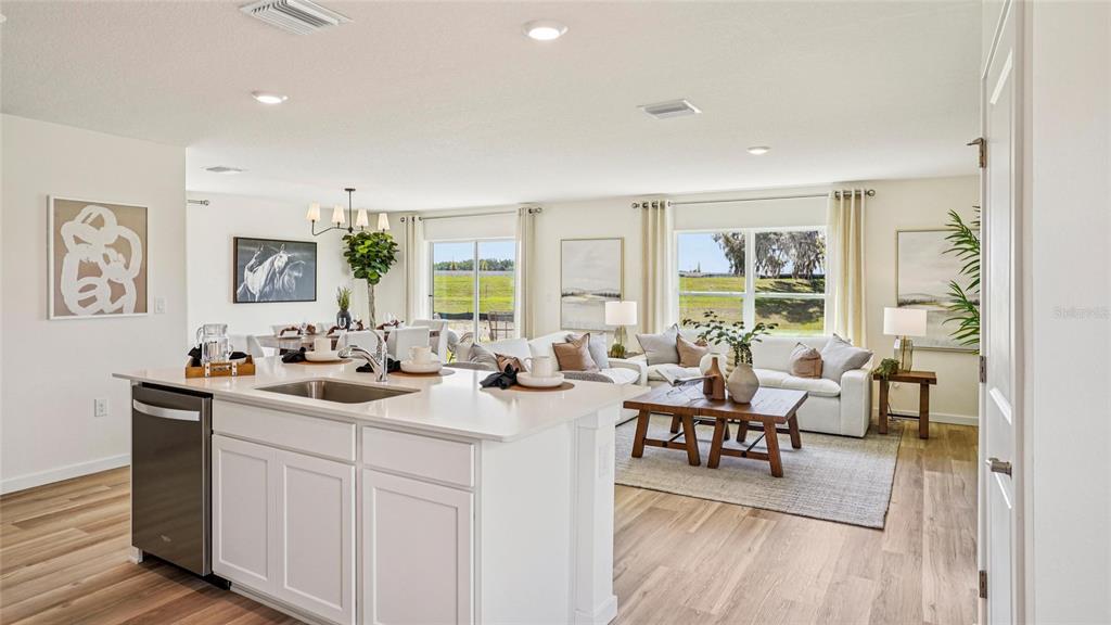 A kitchen island with a sink overlooks an open-concept living and dining area with views — 2118 NE 33RD LANE, OCALA, FL