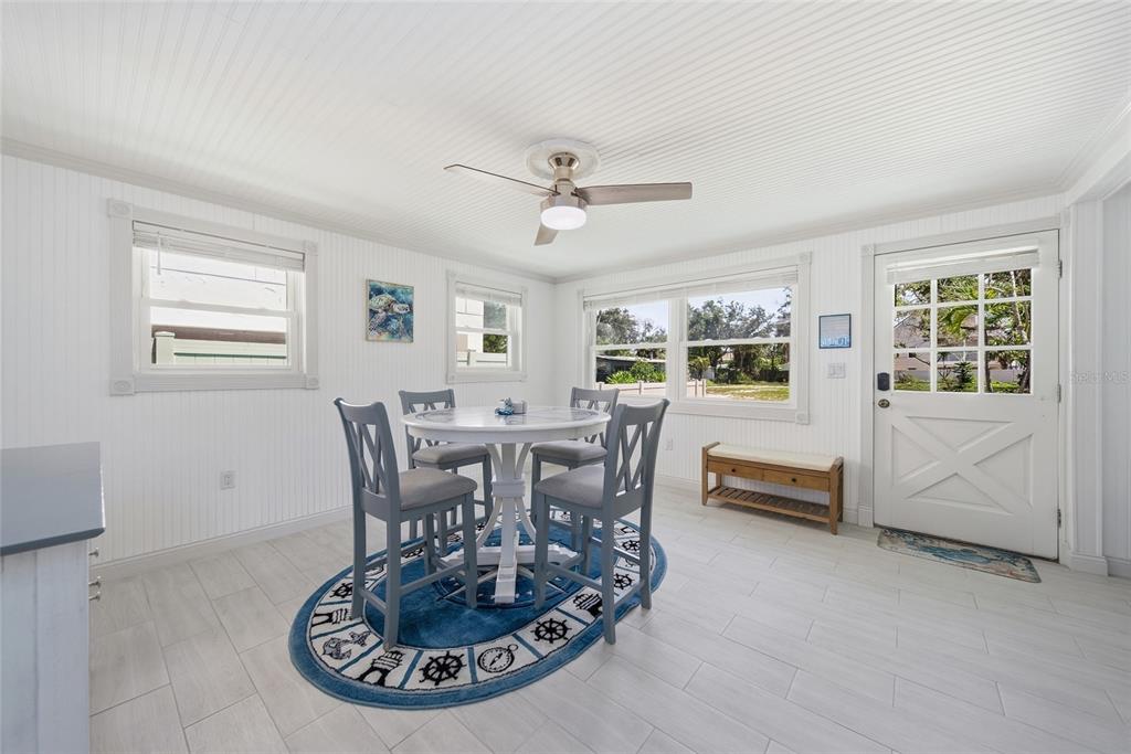 A dining area features a white table, four gray chairs, a nautical rug, and beadboard walls — 104 12TH AVENUE, INDIAN ROCKS BEACH, FL