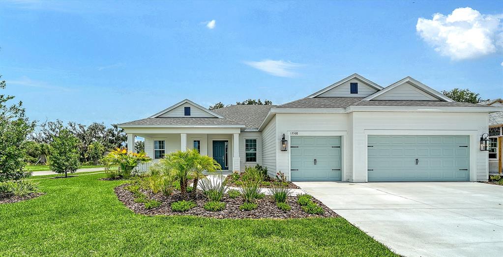 A single-story house with white siding, a light blue garage door, and a front porch — 13508 WILDWATER COURT, PARRISH, FL