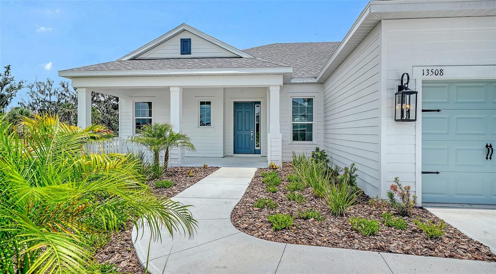 A single-story house with white siding, a covered porch, and a blue front door — 13508 WILDWATER COURT, PARRISH, FL