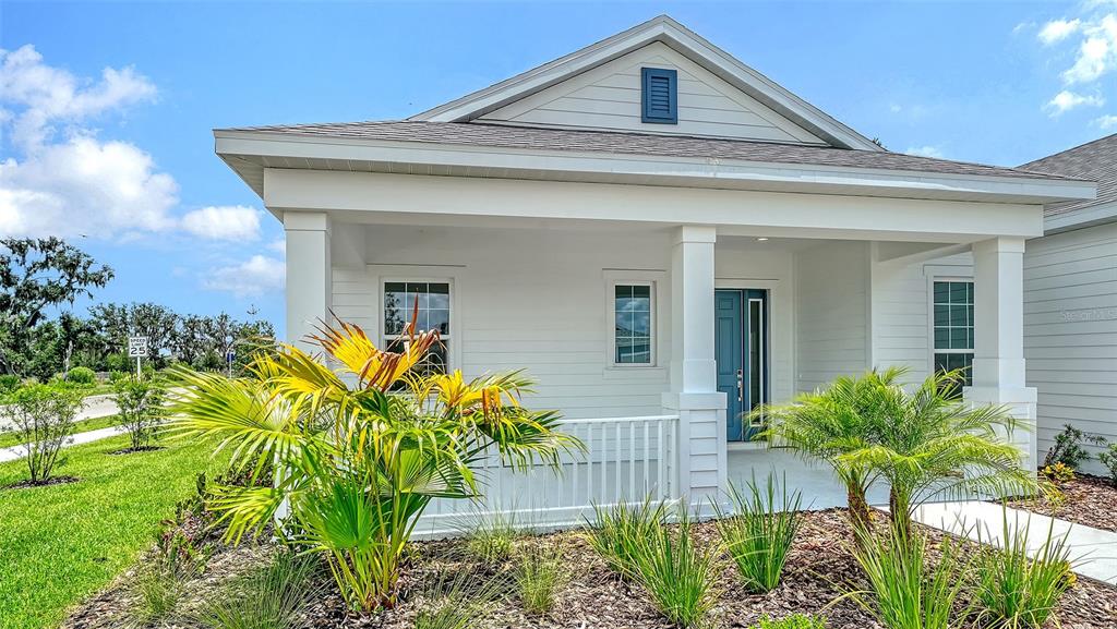 A single-story house with a white porch, blue front door, and palm landscaping — 13508 WILDWATER COURT, PARRISH, FL