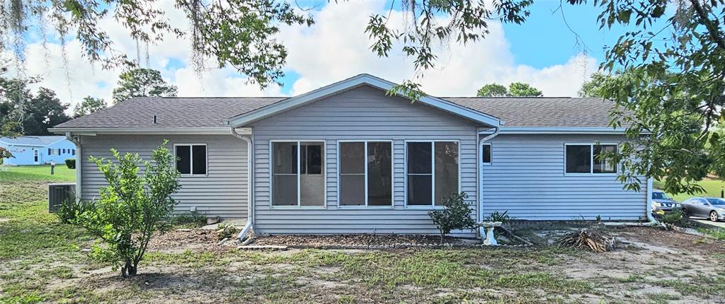 The exterior of a light gray, single-story house with a gabled roof and vinyl siding — 8543 SW 107TH LANE, OCALA, FL