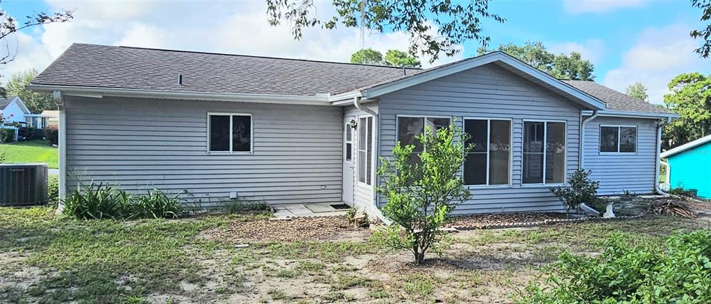 The exterior of a light gray, single-story house with a shingled roof and vinyl siding — 8543 SW 107TH LANE, OCALA, FL