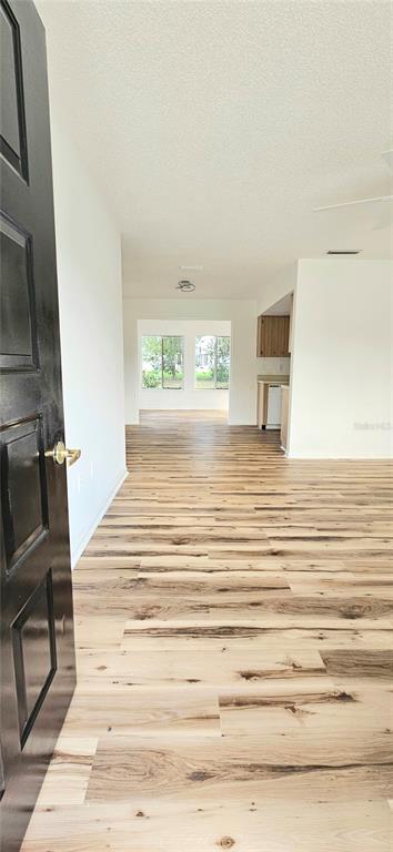 A view from an open doorway into a living area with light wood-look flooring — 8543 SW 107TH LANE, OCALA, FL