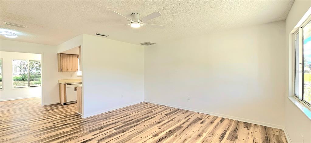 An interior view shows a living area with wood-look flooring, a ceiling fan, and an adjacent kitchen — 8543 SW 107TH LANE, OCALA, FL