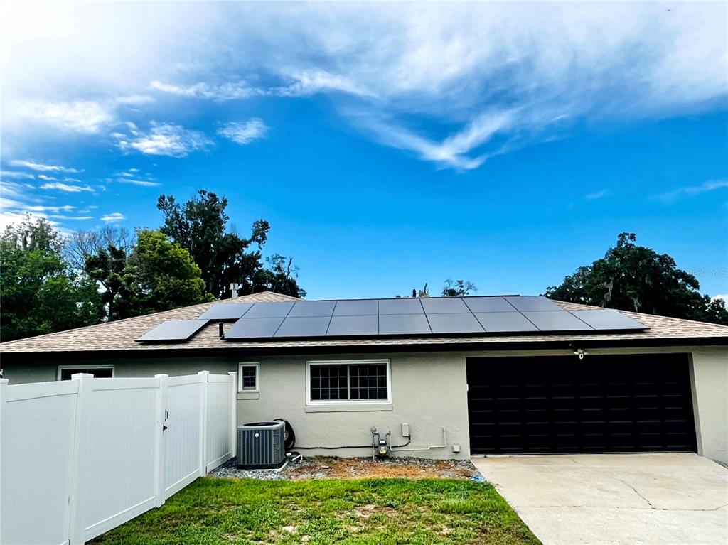The exterior of a house features a shingled roof with solar panels and a garage — 3370 SE 31ST TERRACE, OCALA, FL
