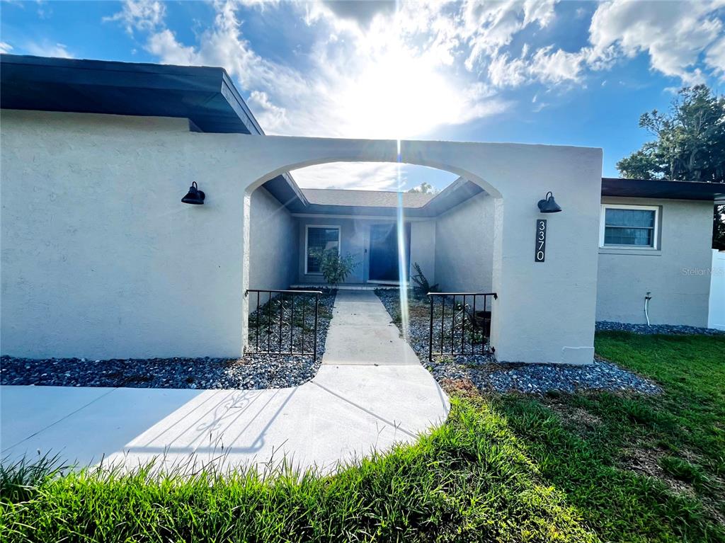A concrete walkway leads through a stucco archway to the front entrance of a house — 3370 SE 31ST TERRACE, OCALA, FL