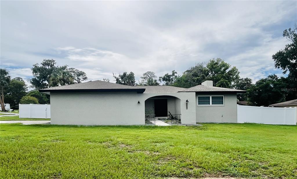 A single-story house with a gray stucco exterior, a recessed entryway, and white vinyl fencing — 3370 SE 31ST TERRACE, OCALA, FL