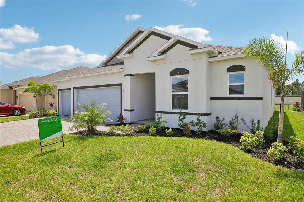 A single-story house with a white stucco exterior, a two-car garage, and a green sign — 25129 CALUSA DRIVE, PUNTA GORDA, FL