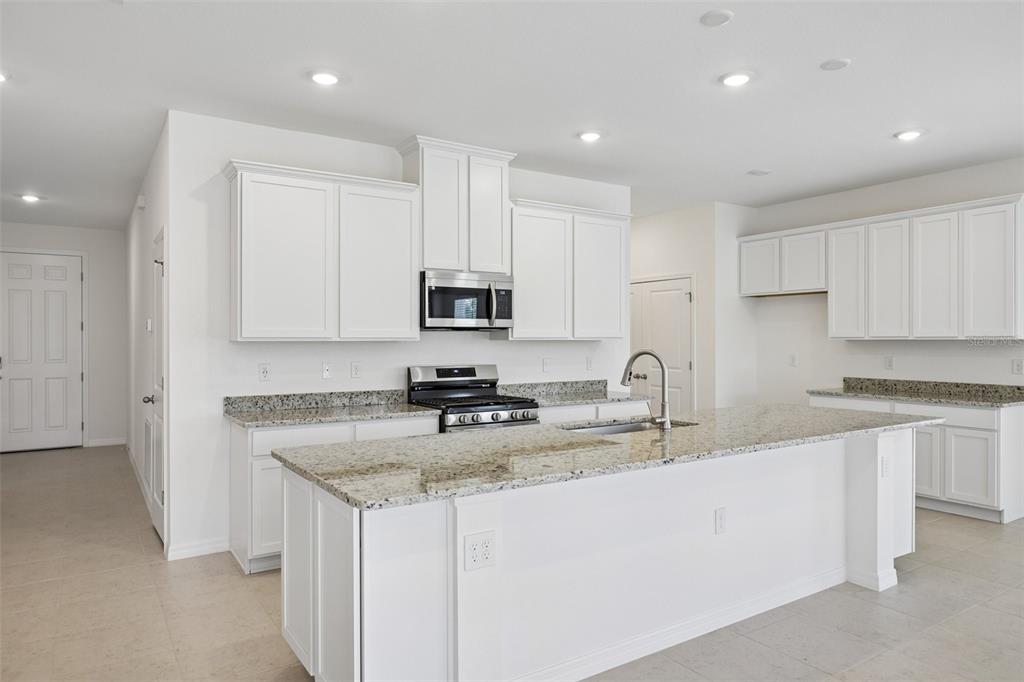 A kitchen with white cabinets, granite countertops, a center island, and stainless steel appliances — 25129 CALUSA DRIVE, PUNTA GORDA, FL
