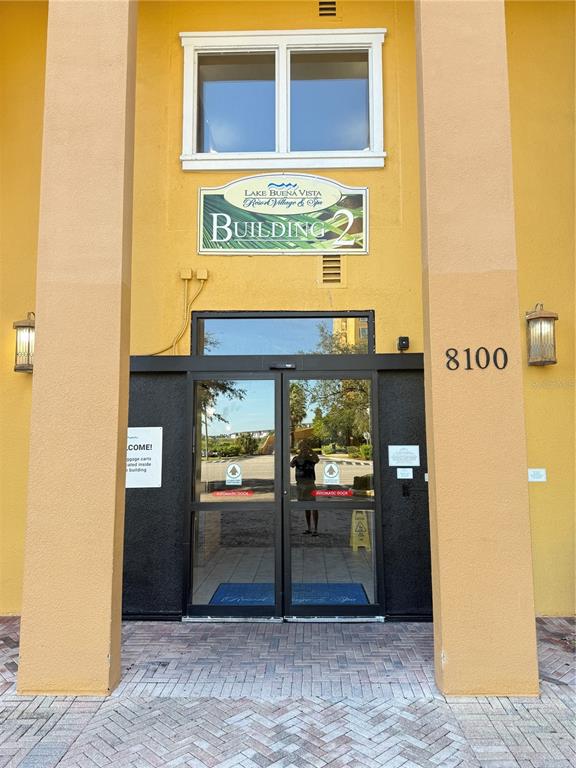The exterior entrance to Building 2 features a glass double door under a yellow facade — 8100 POINCIANA BOULEVARD UNIT 2601, ORLANDO, FL