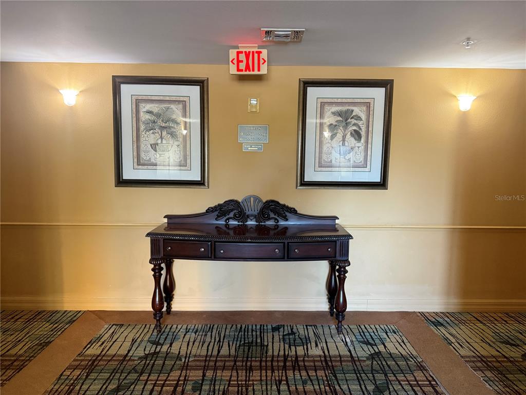 A hallway features a wooden console table centered between two framed botanical prints on yellow walls — 8100 POINCIANA BOULEVARD UNIT 2601, ORLANDO, FL