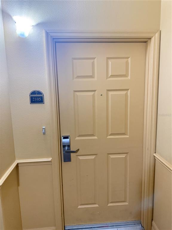 A beige interior door with a metal electronic lock and a unit number sign — 8100 POINCIANA BOULEVARD UNIT 2601, ORLANDO, FL