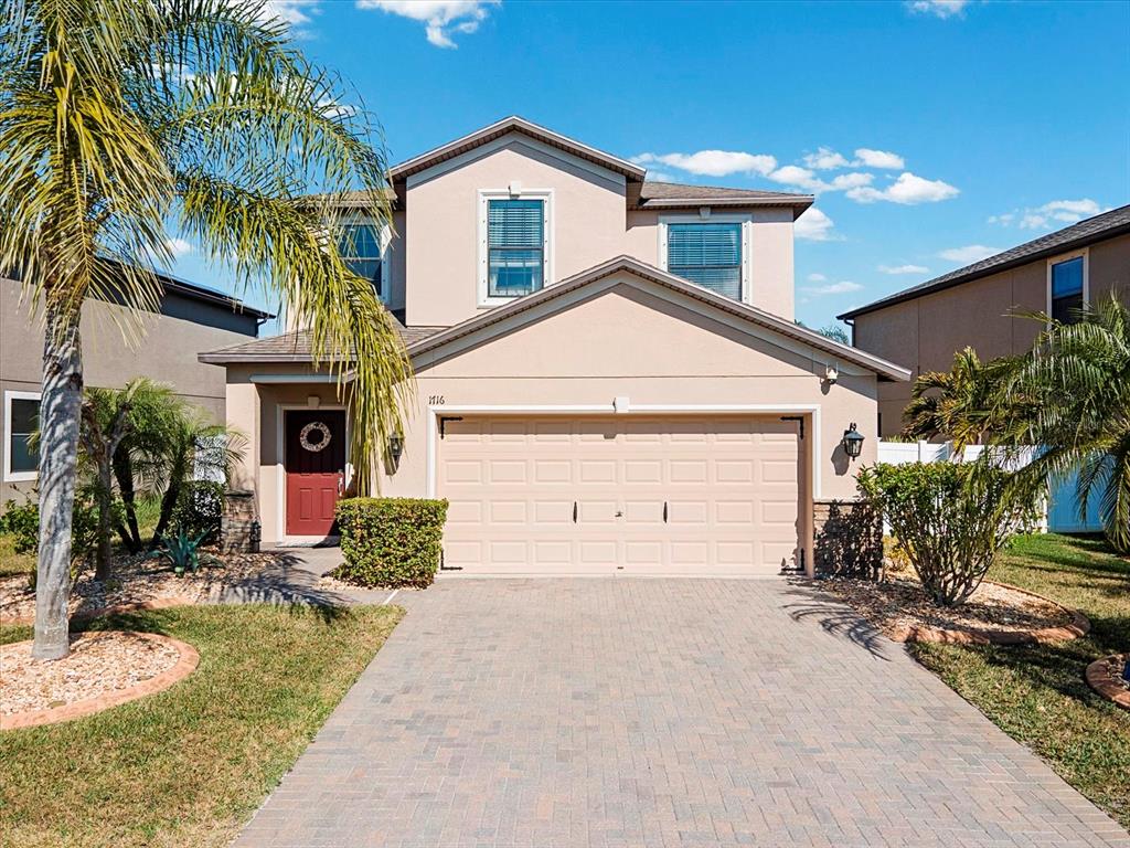 A two-story suburban house with a beige stucco exterior, a two-car garage, and a palm tree — 1716 HADDEN HALL PLACE, TRINITY, FL