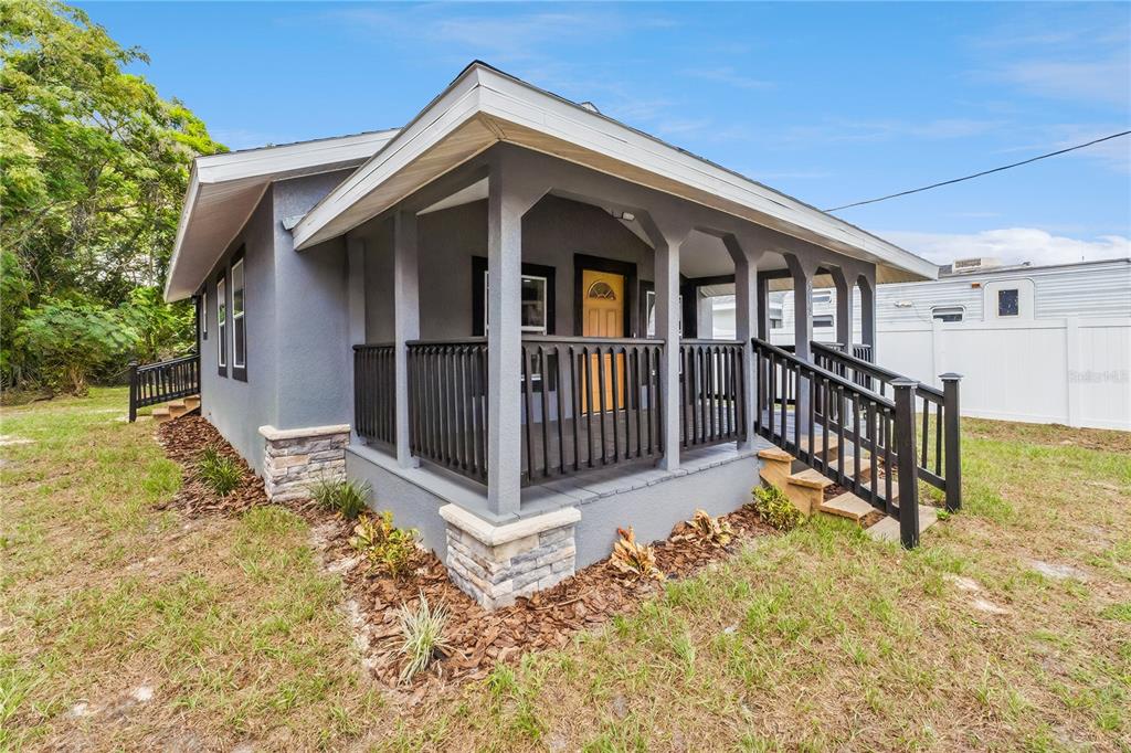 A gray house with a covered front porch, stone accents, and a wooden front door — 512 BENNETT STREET, AUBURNDALE, FL
