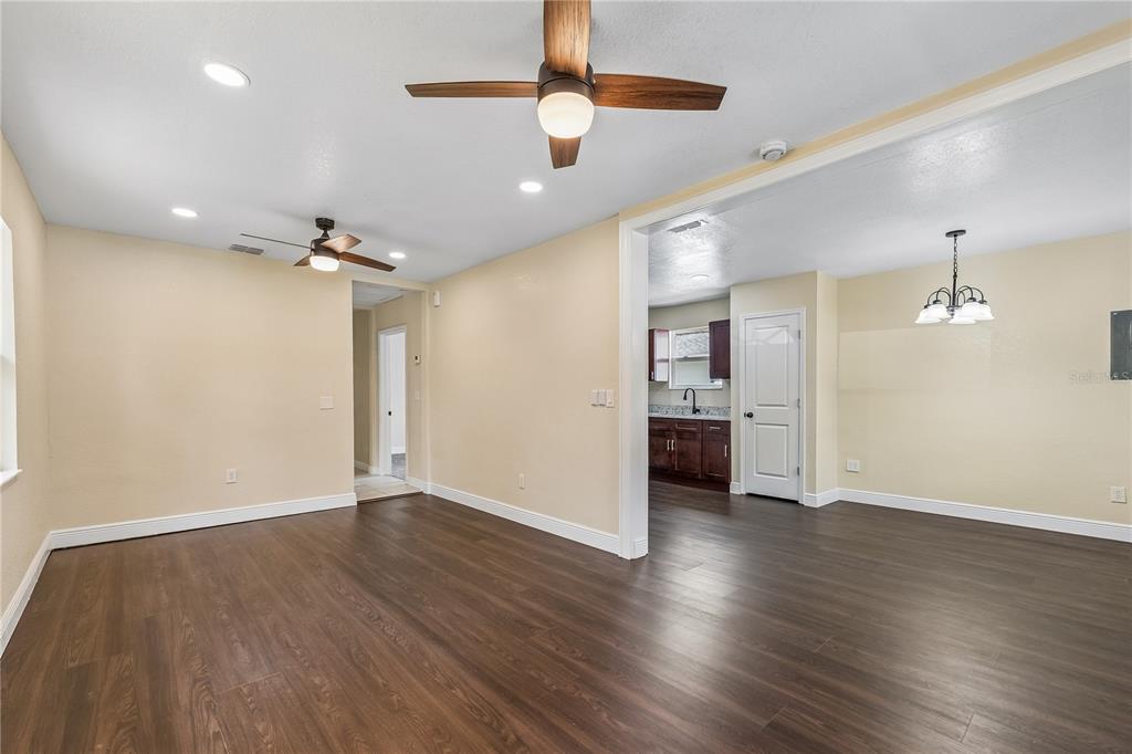 An open-concept living and dining area with wood-look flooring, ceiling fans, and a kitchen view — 512 BENNETT STREET, AUBURNDALE, FL