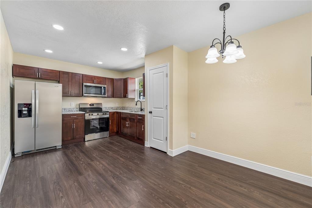 A kitchen with dark wood cabinets, stainless steel appliances, and wood-look flooring — 512 BENNETT STREET, AUBURNDALE, FL