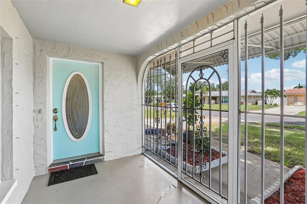A covered porch features a light blue front door and white metal security screen doors — 13178 88TH AVENUE N, SEMINOLE, FL