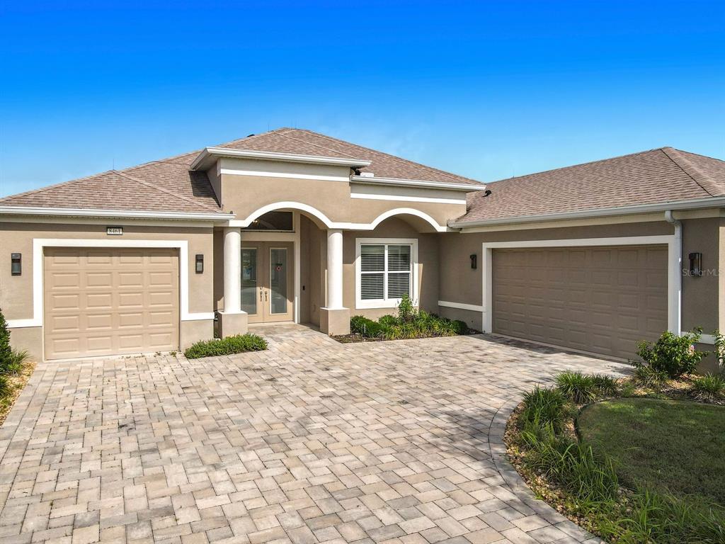 A single-story house with a paved driveway, two garage doors, and a covered front entrance — 8461 BRIDGEPORT BAY CIRCLE, MOUNT DORA, FL