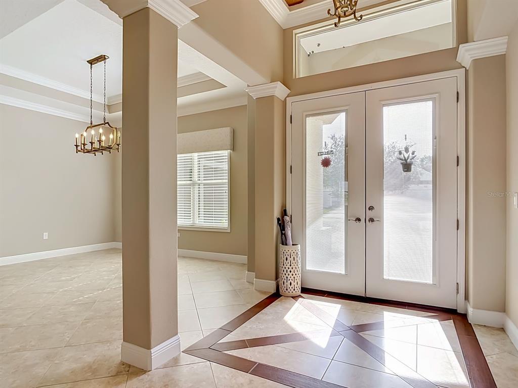 An entryway with tile flooring, double glass doors, and a view into an adjacent room — 8461 BRIDGEPORT BAY CIRCLE, MOUNT DORA, FL